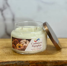 Load image into Gallery viewer, Cashmere Pumpkin candle in a glass jar with a metal lid on a wooden surface.