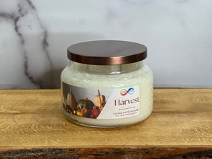 Jar candle labeled 'Harvest' on a wooden surface with a marble background Jar candle labeled 'Harvest' on a wooden surface with a marble background
