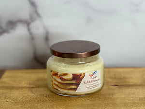 Jar of 'Maple Walnut Pancake' candle on a wooden surface with a marble background Jar of 'Maple Walnut Pancake' candle on a wooden surface with a marble background