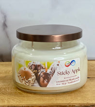 Load image into Gallery viewer, Candle jar labeled 'Sticky Apple' with a decorative label on a wooden surface.