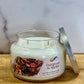 Candle jar labeled 'Evergreen & Apples' on a wooden surface with a marble background