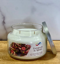 Load image into Gallery viewer, Candle jar labeled &#39;Evergreen &amp; Apples&#39; on a wooden surface with a marble background
