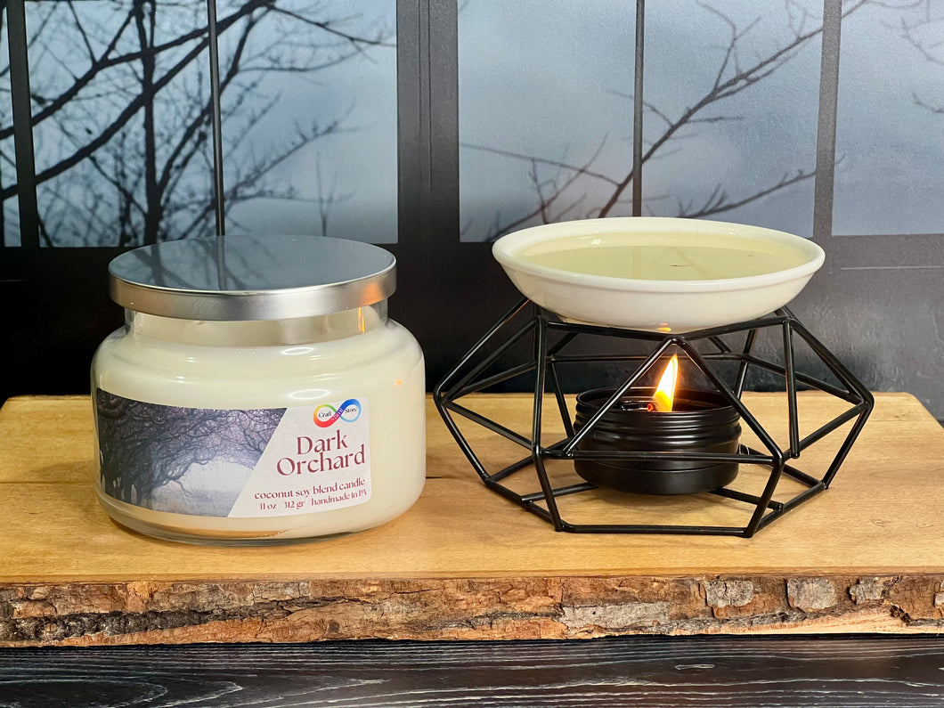 Jar of 'Dark Orchard' candle with a lit wax warmer on a wooden surface.