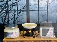Load image into Gallery viewer, Candle and wax melts with packaging on a wooden surface in front of a window with bare trees.
