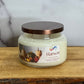 Jar candle labeled 'Harvest' on a wooden surface with a marble background