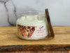 Candle with a 'Maple Leaf & Acorn' label on a wooden surface
