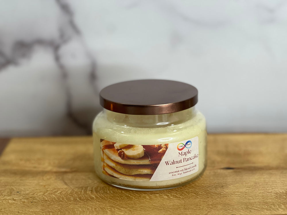 Jar of 'Maple Walnut Pancake' candle on a wooden surface with a marble background