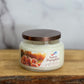 Jar of 'Sassy Pumpkin' candle on a wooden surface with a marble background