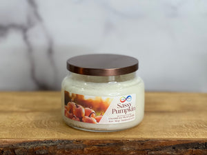 Jar of 'Sassy Pumpkin' candle on a wooden surface with a marble background