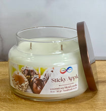 Load image into Gallery viewer, Glass candle jar labeled &#39;Sticky Apple&#39; with a wooden lid on a wooden surface.
