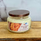 Jar of Sweet Potato Souffle candle on a wooden surface with a marble background